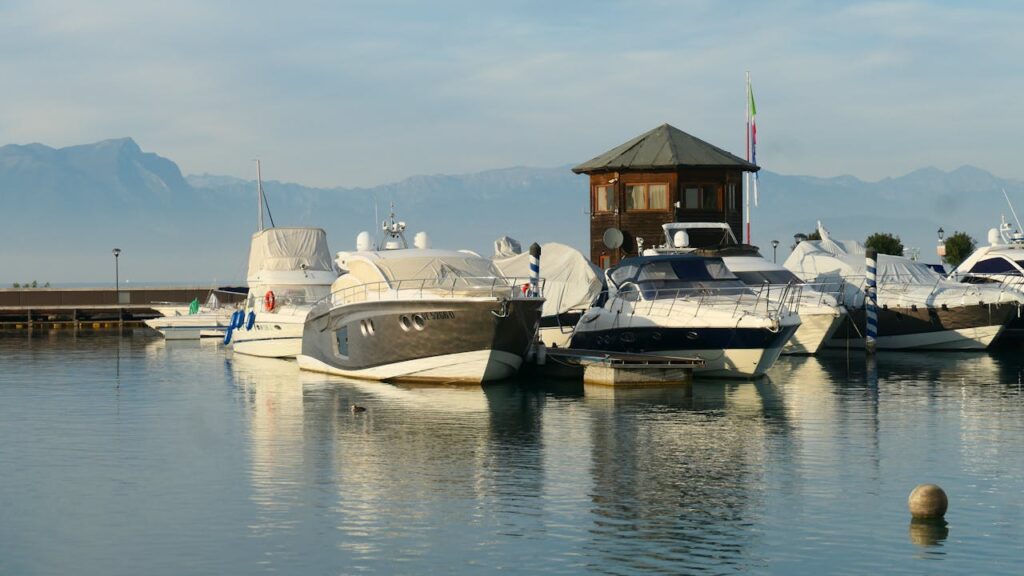 Serene view of yachts docked at Peschiera del Garda with mountains in the background.